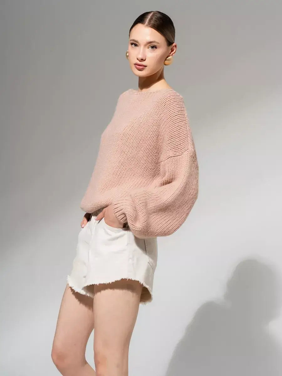 Model wearing the Rosea Sweater by Lauven, an oversized off-shoulder knit in powder pink.