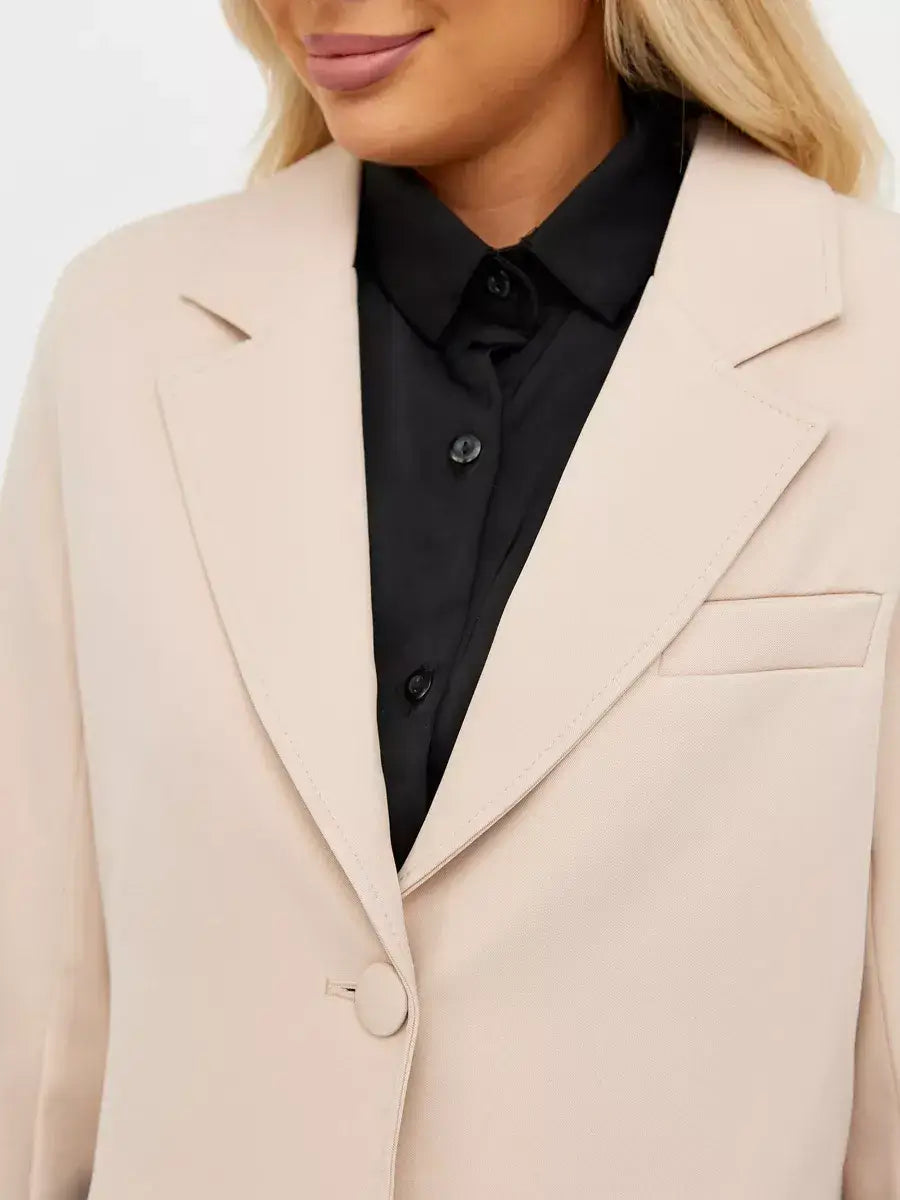 Close-up of a woman wearing a Lauven Sandstone Blazer in soft beige over a black shirt, showcasing classic tailoring.
