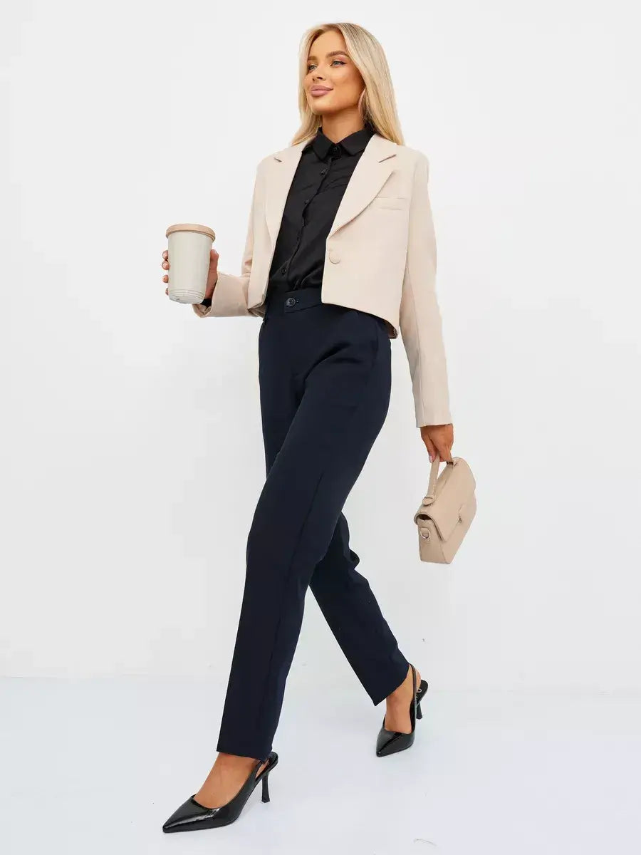 Stylish woman wearing a Sandstone Blazer by Lauven, featuring a cropped design in soft beige, paired with navy trousers.