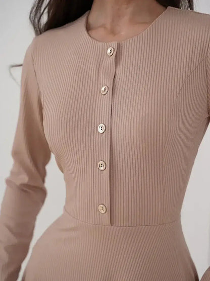 Detail of the Sculpted Ease Midi Dress by Lauven, featuring a ribbed knit texture and gold-tone buttons in a smooth beige hue.