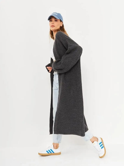 Model wearing Shadow Cardigan, a long oversized knitwear coat by Lauven, styled with casual denim and sneakers.