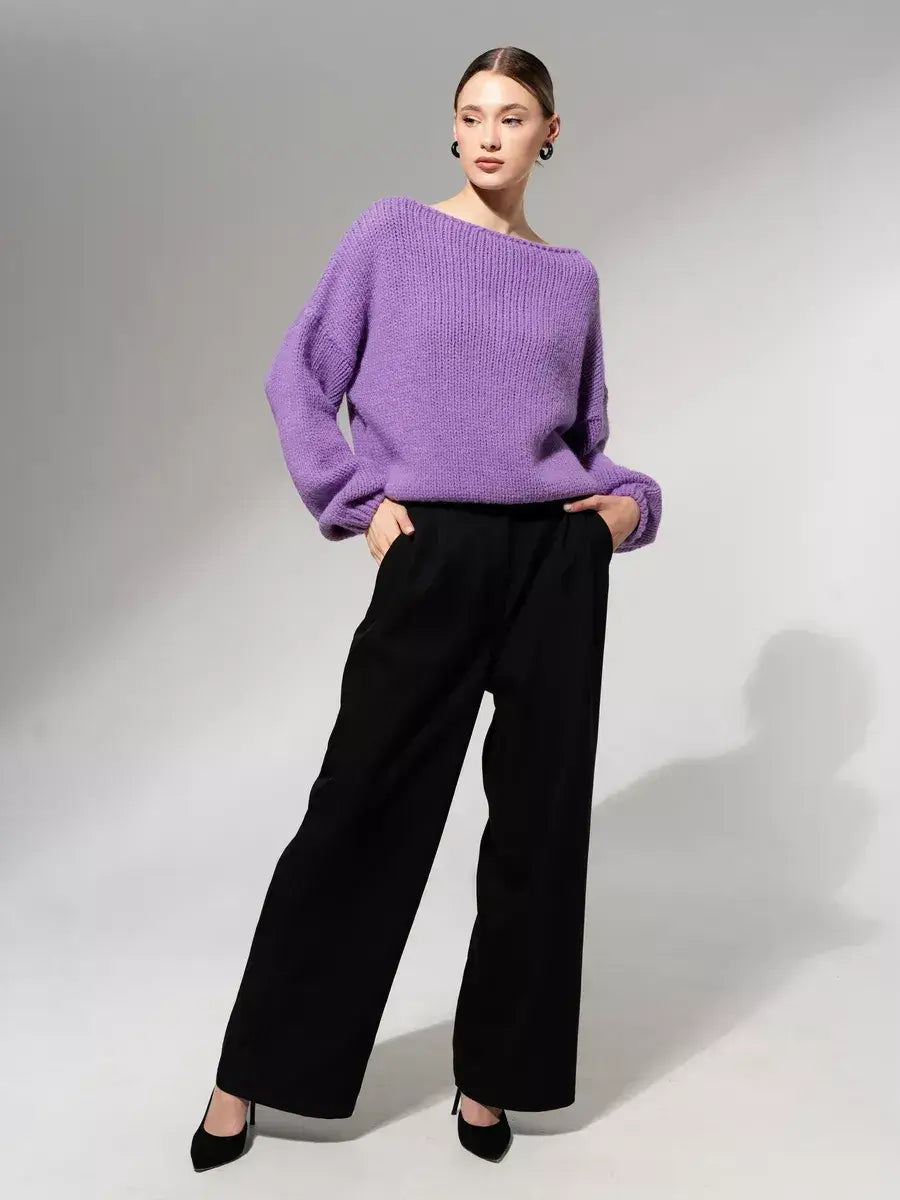 Model wearing the Lavina Sweater by Lauven, an oversized off-shoulder knit in lavender, paired with black wide-leg pants.