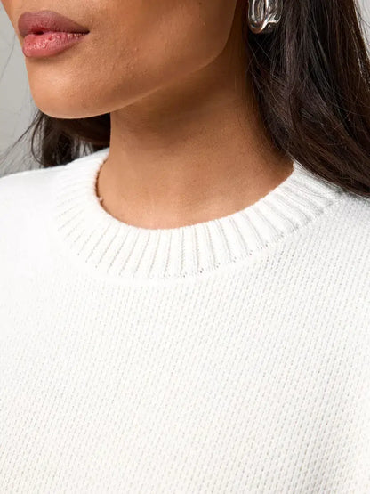 Close-up of a woman wearing the Celeste Pullover by Lauven, showcasing its soft ivory fabric and ribbed neckline.