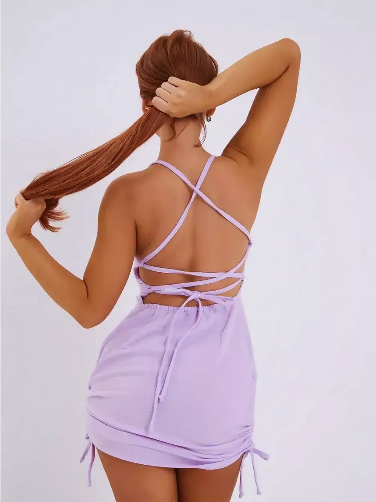 Back view of a model wearing the Lilac Crush mini dress by Lauven, featuring adjustable criss-cross straps.
