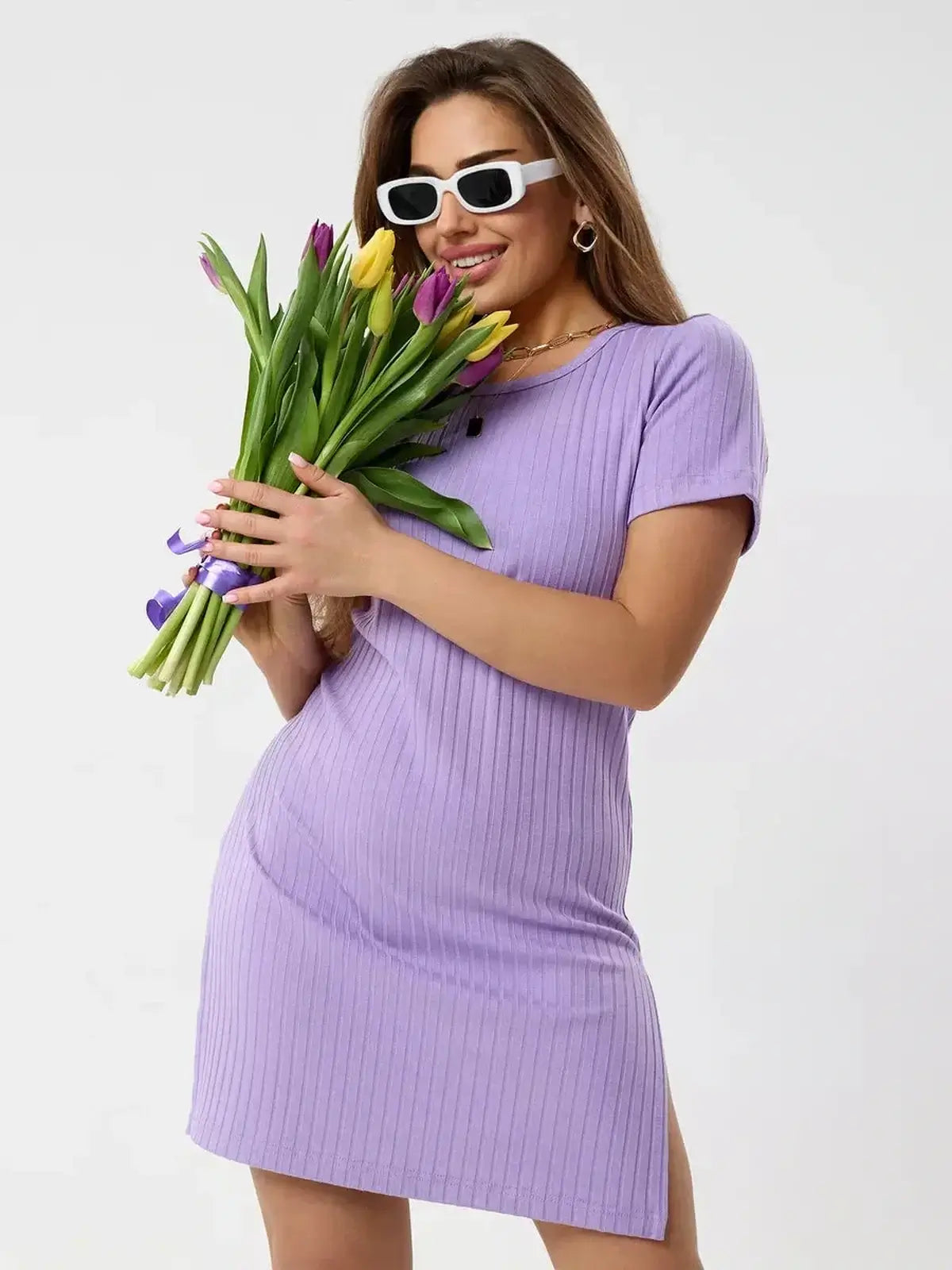 Model wearing the Lilac Ripple mini dress from Lauven, holding a bouquet of tulips in a light violet shade.