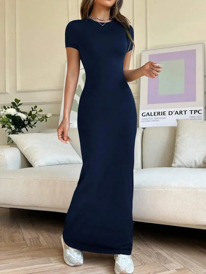 Model wearing Luna Curve Maxi Dress in navy, showcasing sleek silhouette and modern elegance in a living room setting.