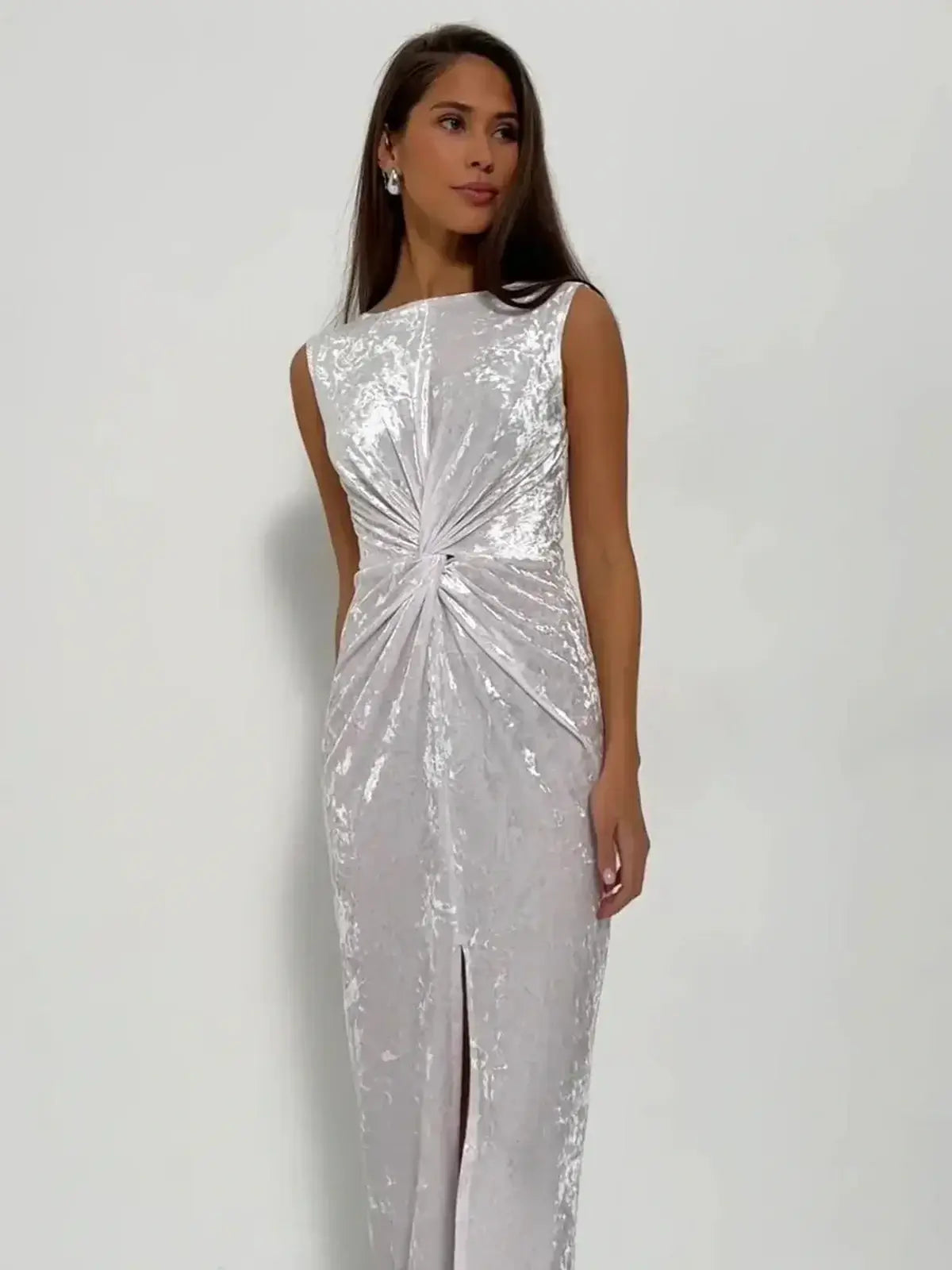 Model wearing the Lustre Twist Maxi Dress in luminous white crushed velvet with a sculptural silhouette and elegant twist detail.