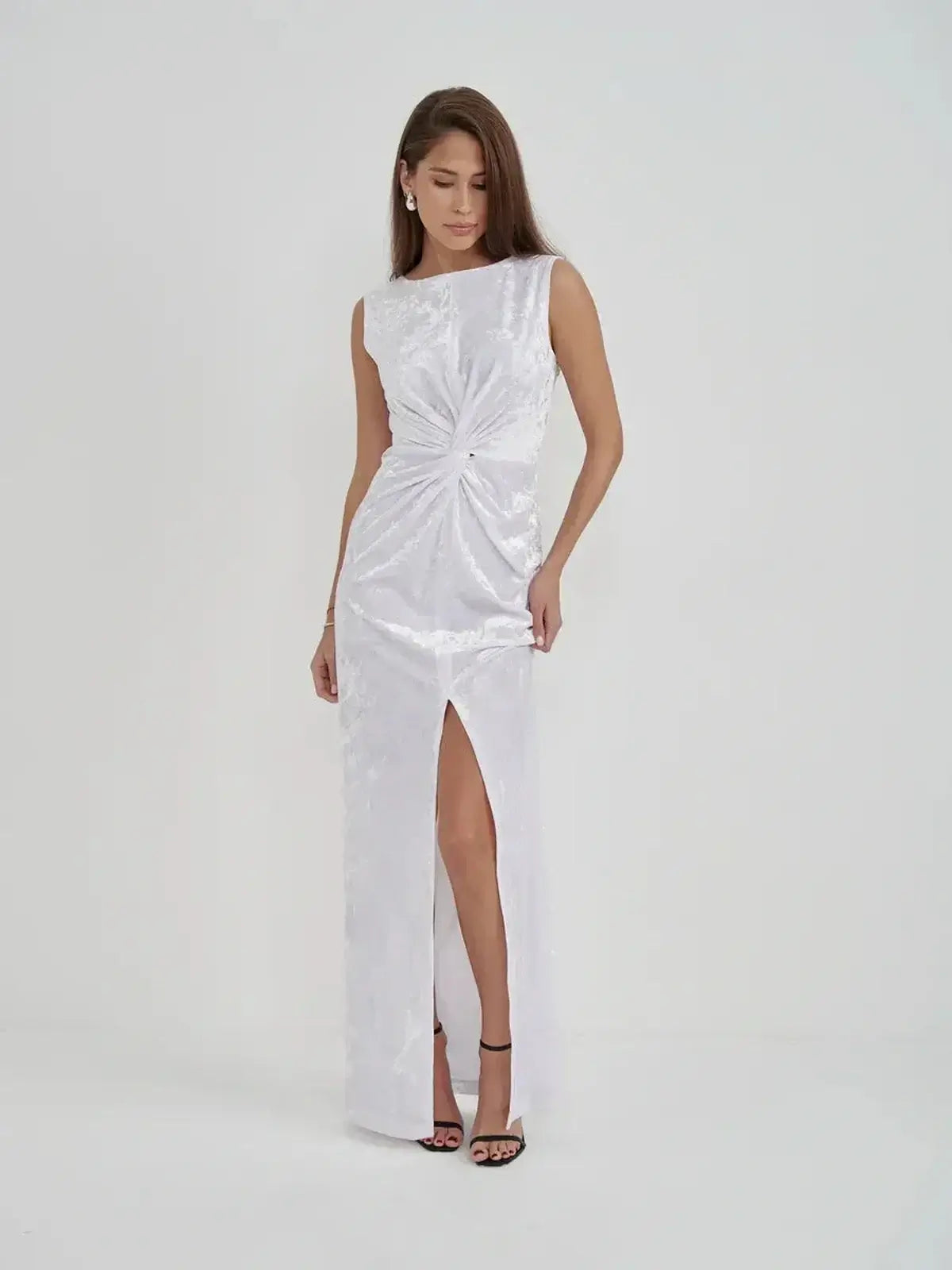 Model showcasing the Lustre Twist Maxi Dress, featuring draped white velvet and a chic slit for elegant evening wear.