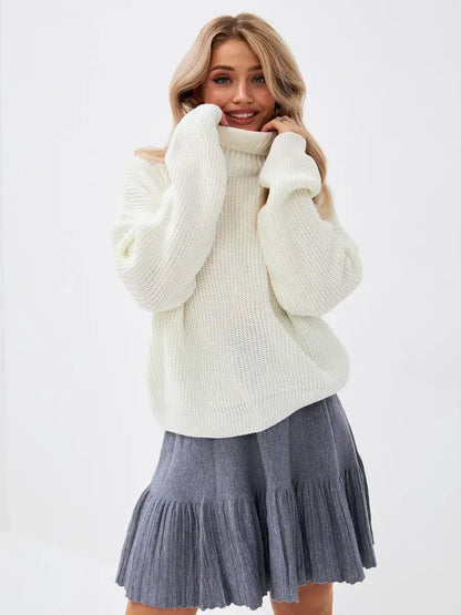 Model wearing the Lyra Sweater by Lauven, an oversized ivory knit with high neck paired with a grey flared skirt.