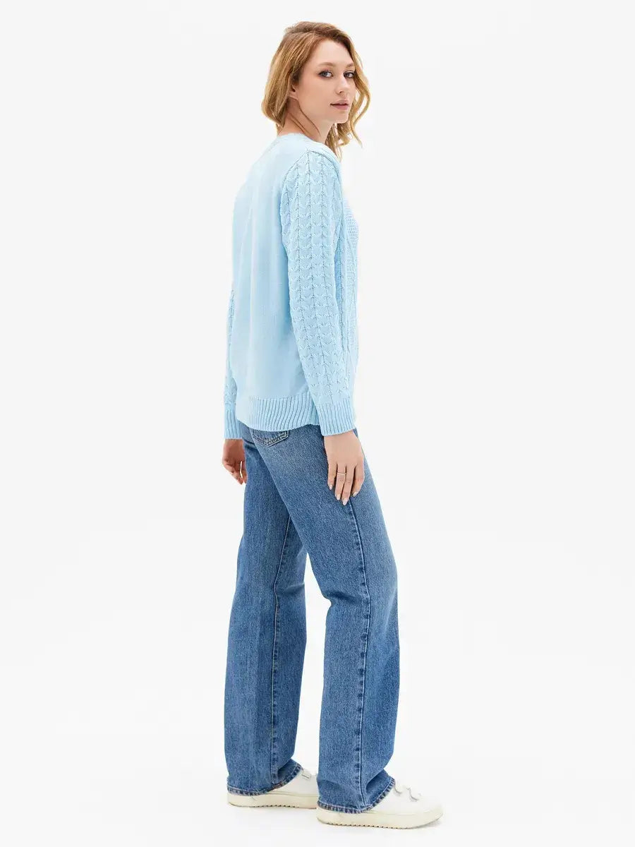 Model wearing the Lyra Sweater in light blue cable knit by Lauven, styled with jeans, showcasing elegance and comfort.