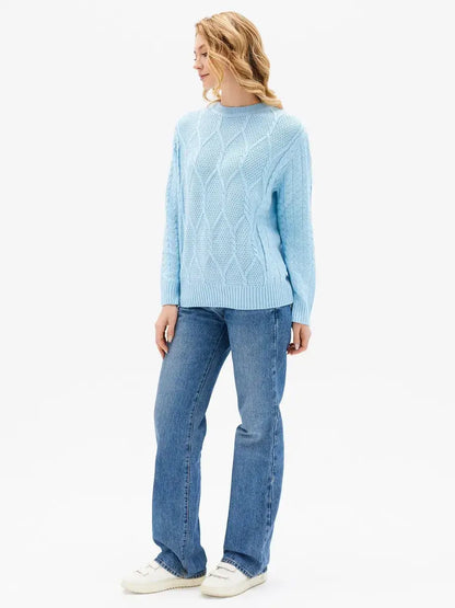 Woman wearing the Lyra Sweater by Lauven in light blue cable knit paired with jeans.