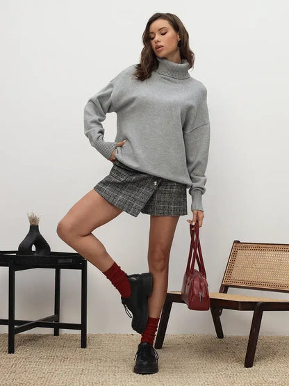 Lyra Sweater by Lauven, light grey turtleneck knitwear styled with a plaid skirt and red accessories.
