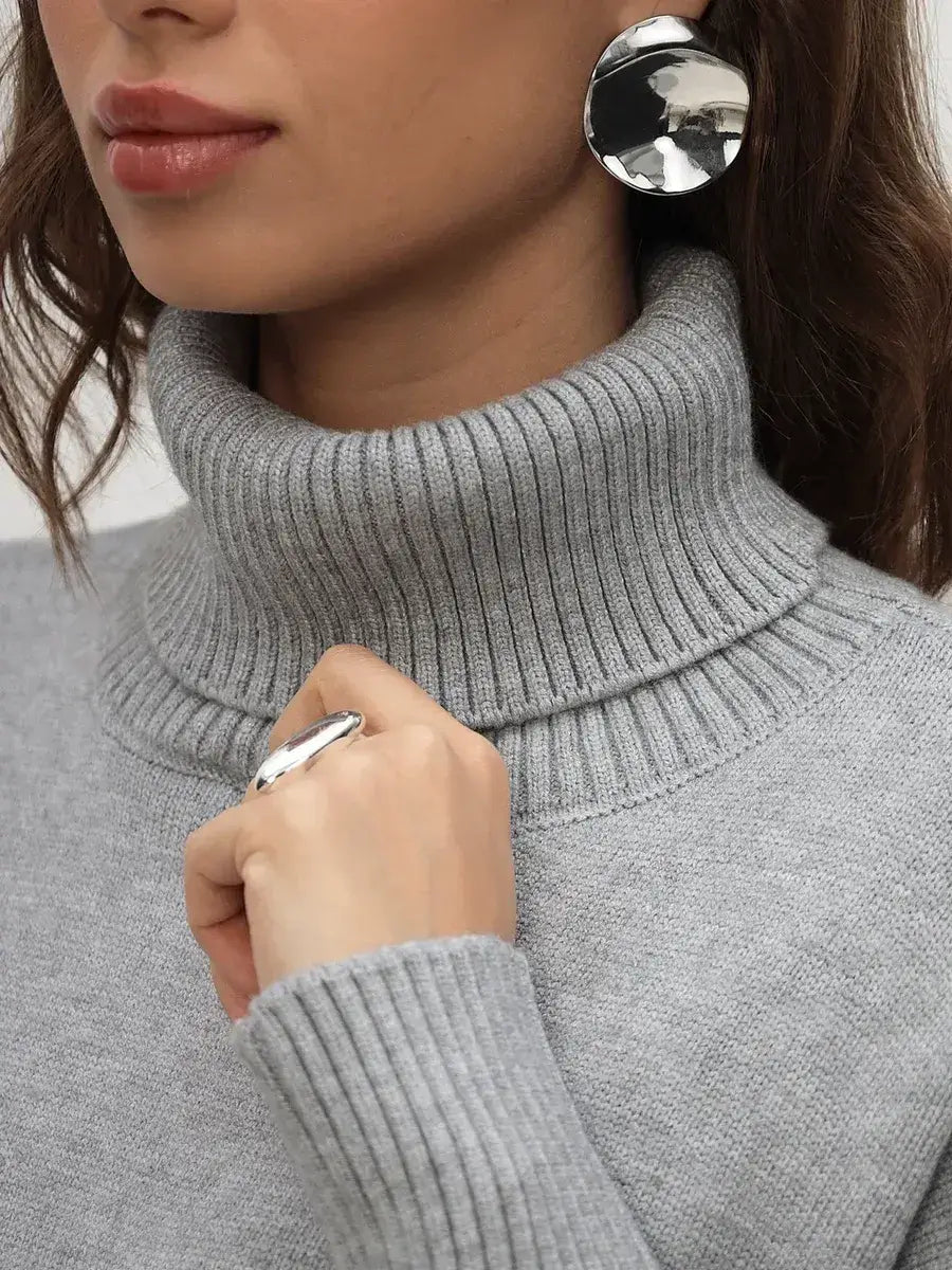 Close-up of a woman wearing a light grey Lyra Sweater by Lauven, showcasing its turtleneck and elegant style.