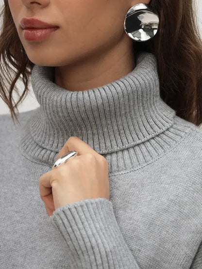 Close-up of a woman wearing a light grey Lyra Sweater by Lauven, showcasing its turtleneck and elegant style.