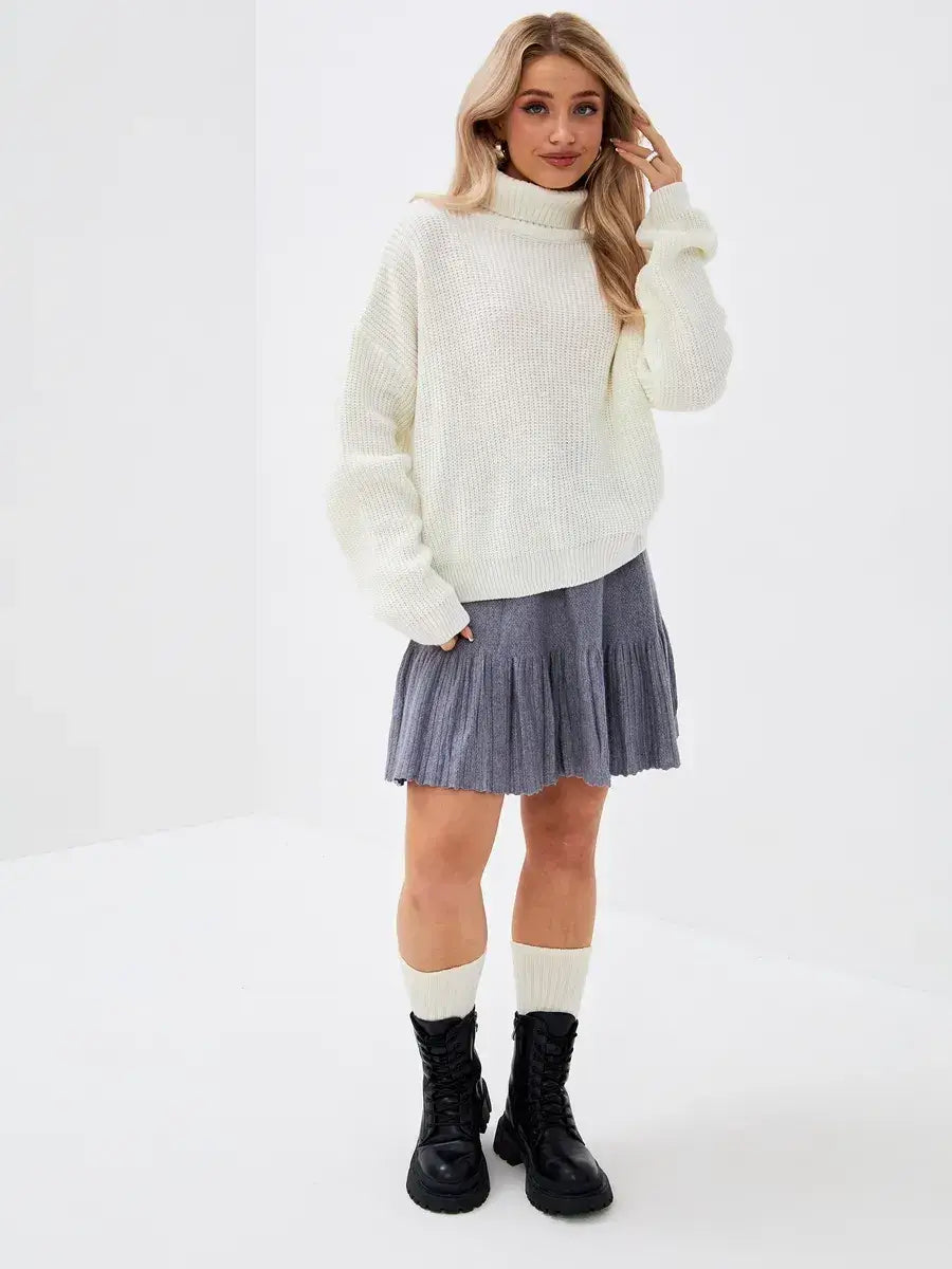 Lyra Sweater by Lauven, oversized knit sweater in ivory with high neck, styled with a pleated skirt and boots.