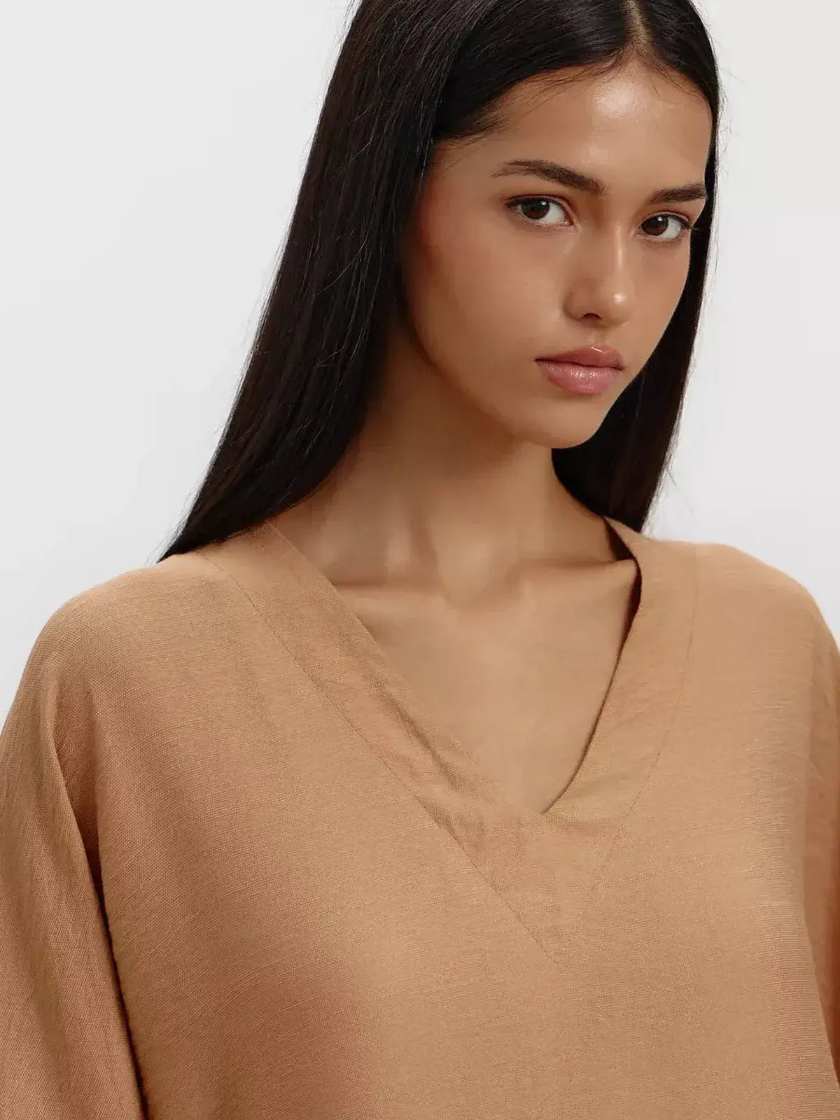 Close-up of a model wearing a soft, sandstone-hued V-neck maxi dress with relaxed sleeves.