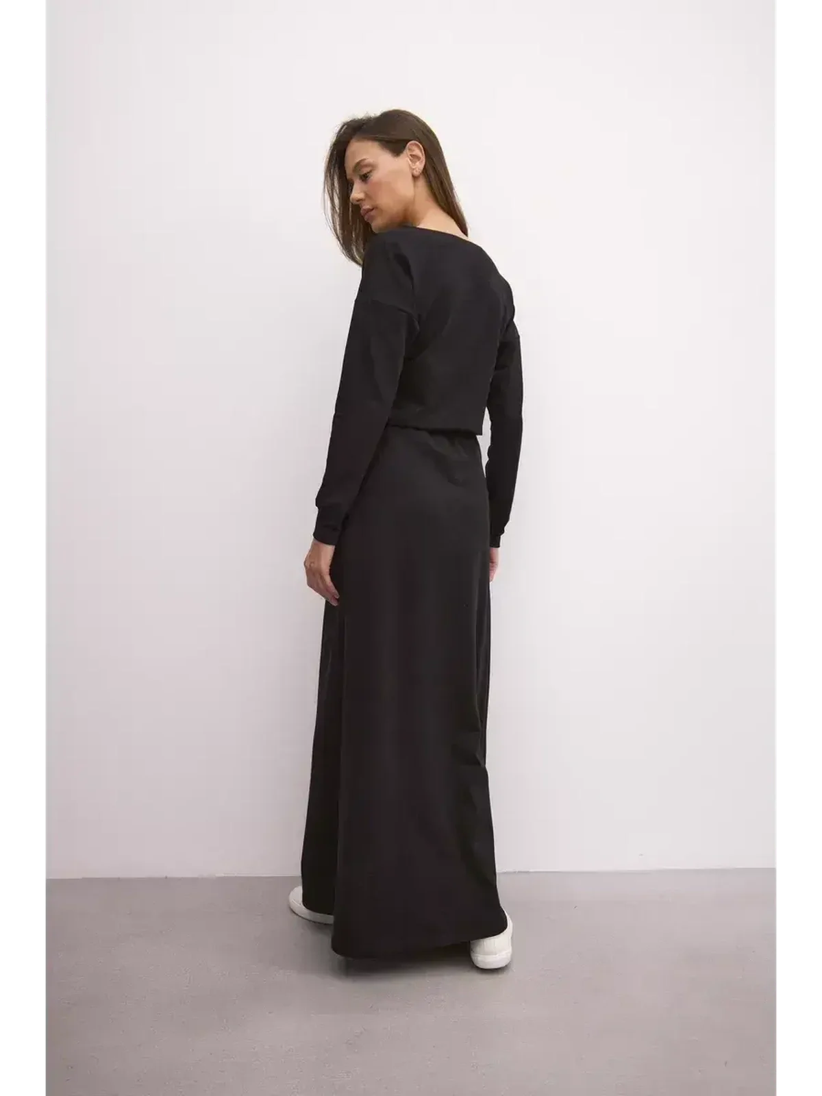 Woman wearing a black maxi dress with a relaxed fit and cinched waist, showcasing urban elegance.