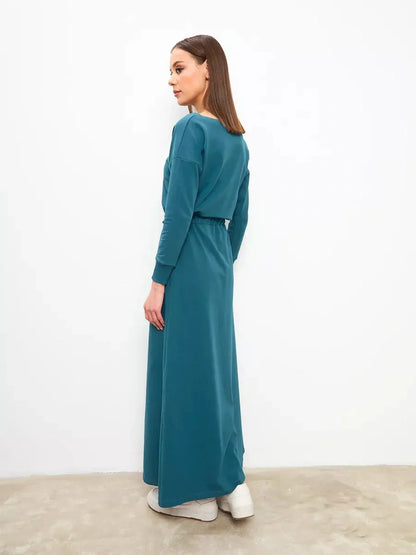 Model showcasing the Maxi Dress Evergreen Ease in forest green, featuring a cinched waist and modern silhouette.
