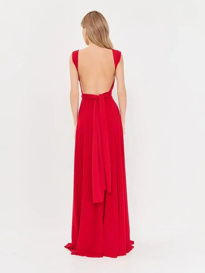 Back view of the Maxi Dress Flame Muse, showcasing a backless design, flowing fabric, and elegant bow detail in bold red.