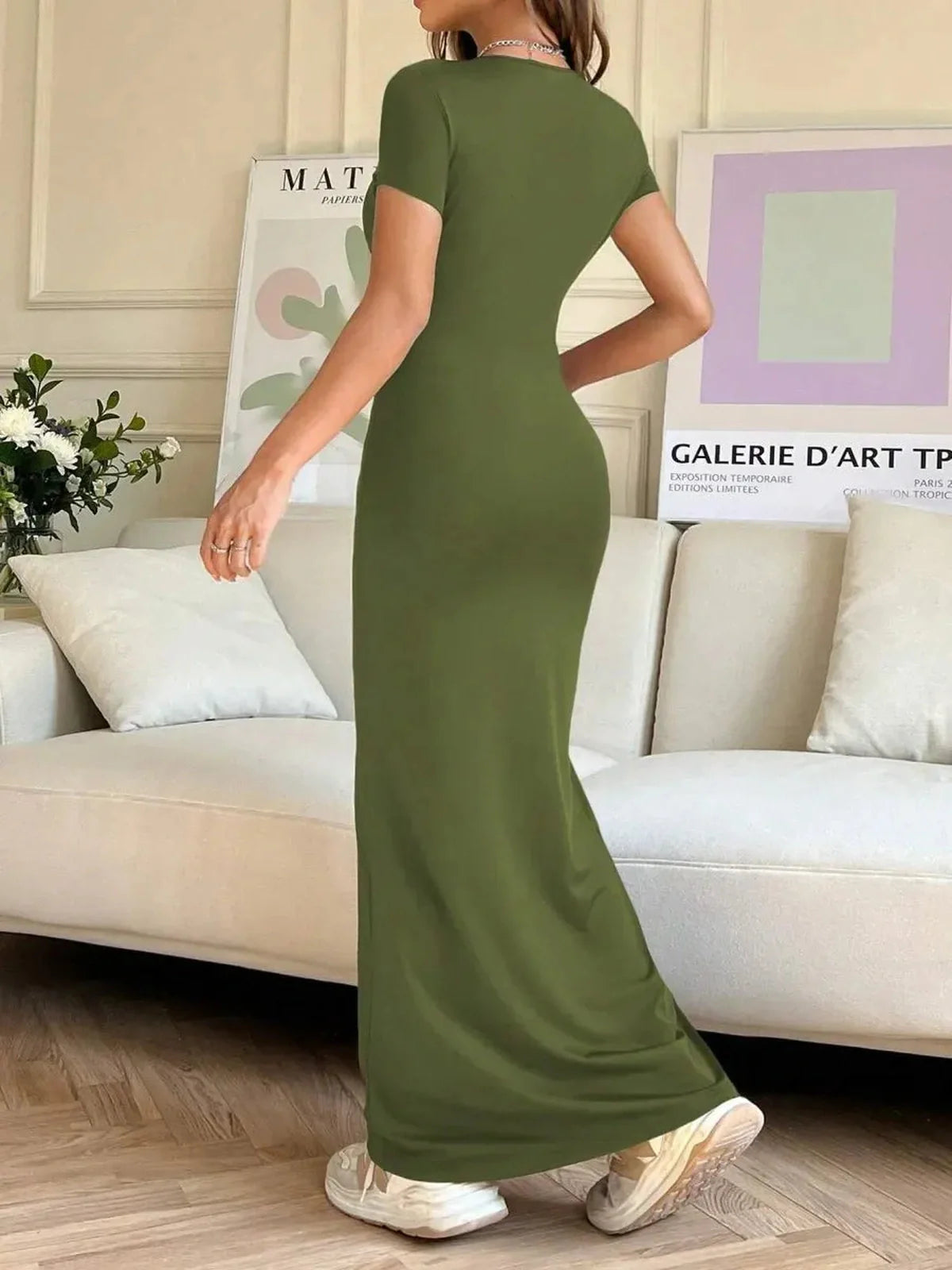 Woman wearing an olive green maxi dress, showcasing a sculpting silhouette in a stylish indoor setting.