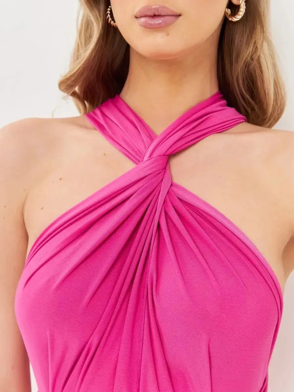 Close-up of a woman's neckline in a fuchsia pink maxi dress with a twisted halter design.
