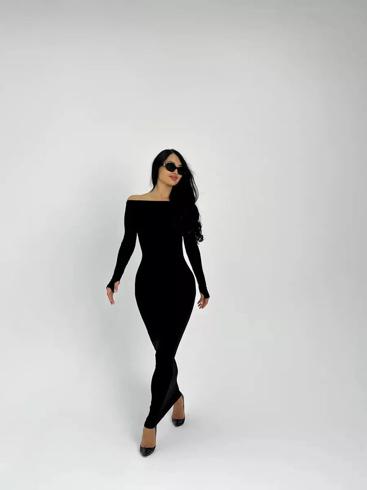 Model in a sleek black Maxi Dress Noir Allure with long sleeves and a boat neckline, showcasing an elegant silhouette.