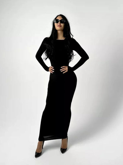 Model wearing the Maxi Dress Noir Allure, a sleek black long sleeve bodycon dress with sunglasses.