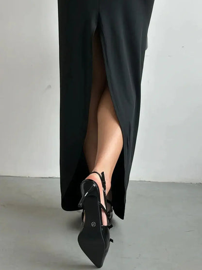 Thigh-high slit detail of the Maxi Dress Obsidian Charm paired with sleek black heels.