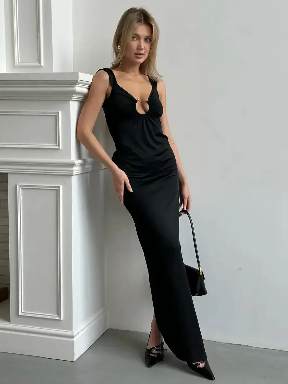 Model wearing the Maxi Dress Obsidian Charm with a plunging neckline and gold ring detail, showcasing a sultry silhouette.