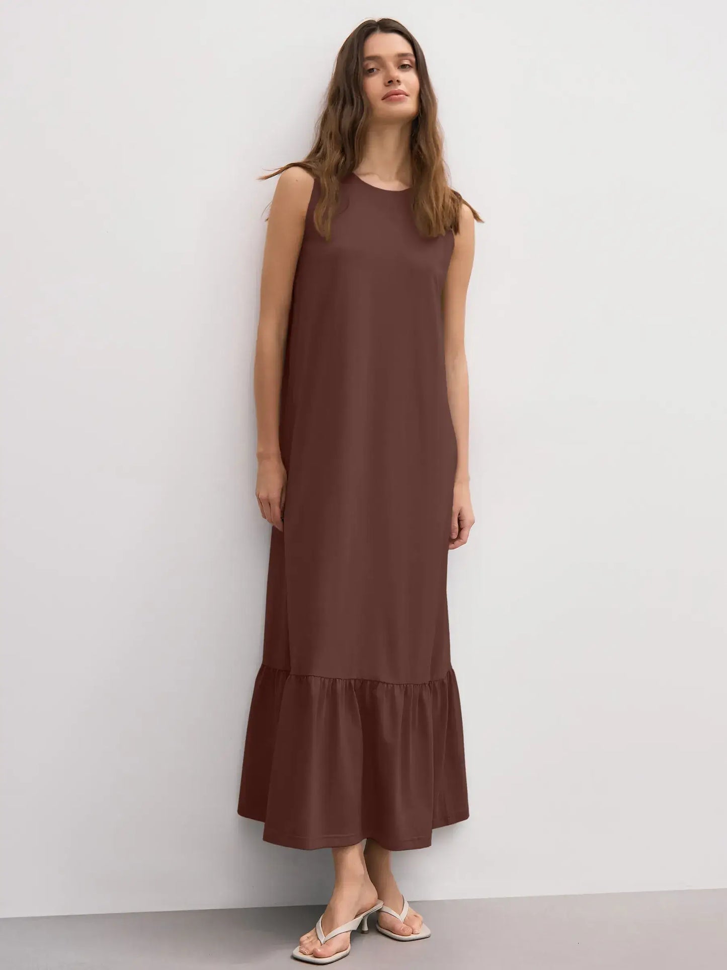 Model wearing a chocolate-hued sleeveless maxi dress with ruffle hem, showcasing chic elegance and everyday style.