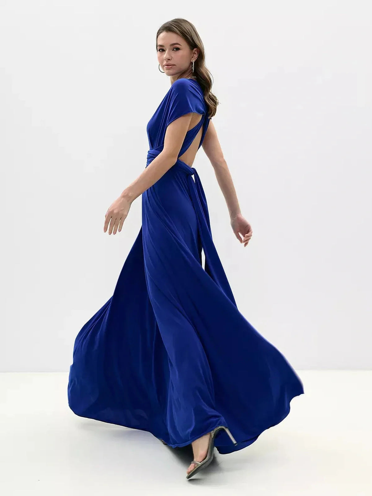 Model showcasing the Maxi Dress Sapphire Twist in vibrant blue, featuring a twisted open back and flowing silhouette.