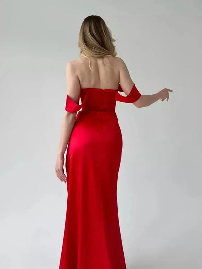 Back view of a woman in a red satin Maxi Dress Scarlet Muse with corset detailing and off-shoulder sleeves.