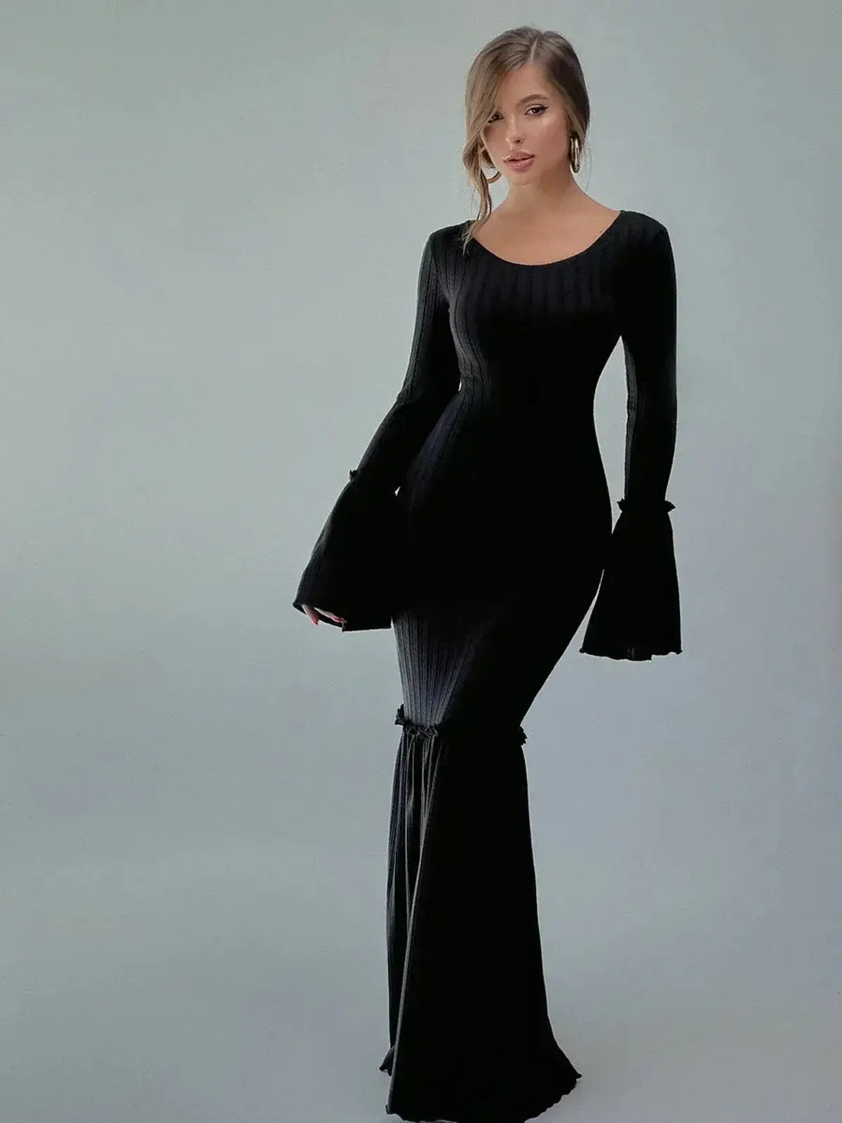 Model wearing the Meridian Maxi Dress, a black ribbed knit gown with flared cuffs and hem, exuding elegance.