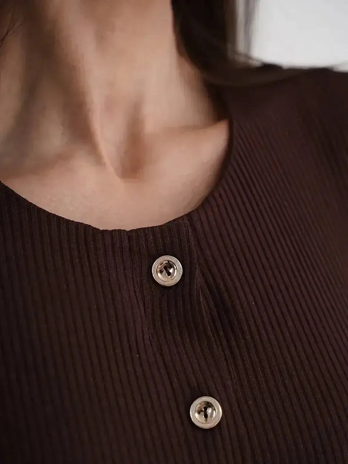 Close-up of the decorative button detailing on the Midi Dress Noirette by Lauven, showcasing its elegant ribbed texture.