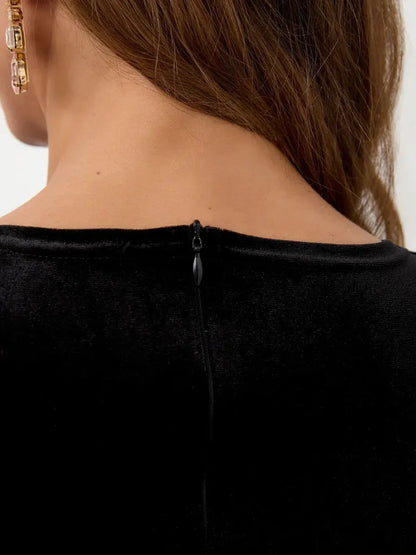 Back view of the Midnight Allure Maxi Dress showcasing black velvet fabric and zipper detail.