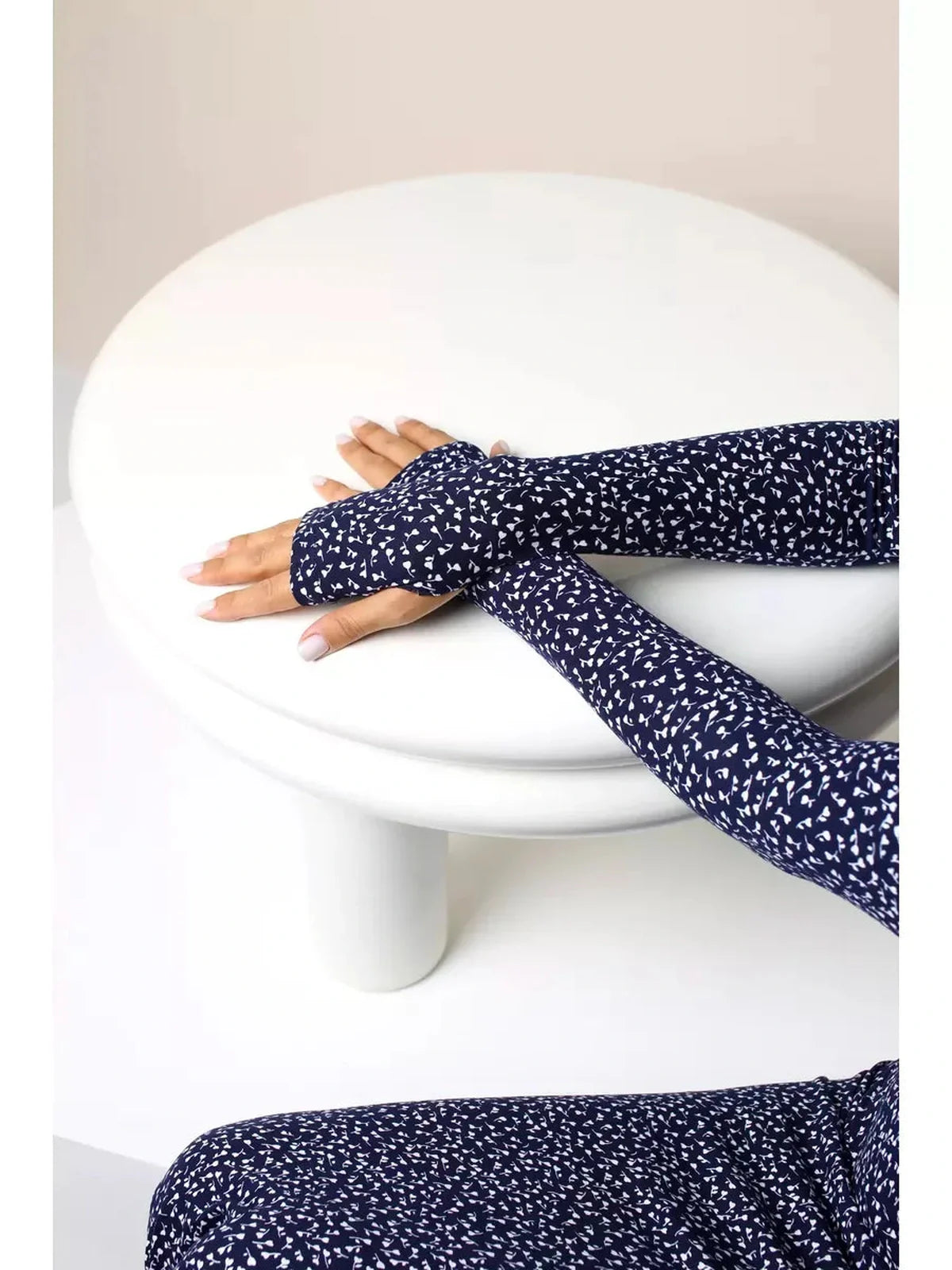 Close-up of hands wearing the Midnight Curve Maxi Dress with thumbhole sleeves on a white table.