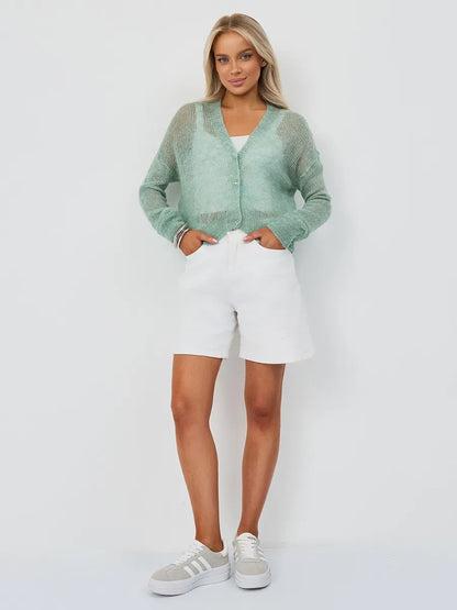 Model wearing Lauven Mint Cardigan, an oversized mohair-blend knitwear in soft green, paired with white shorts.