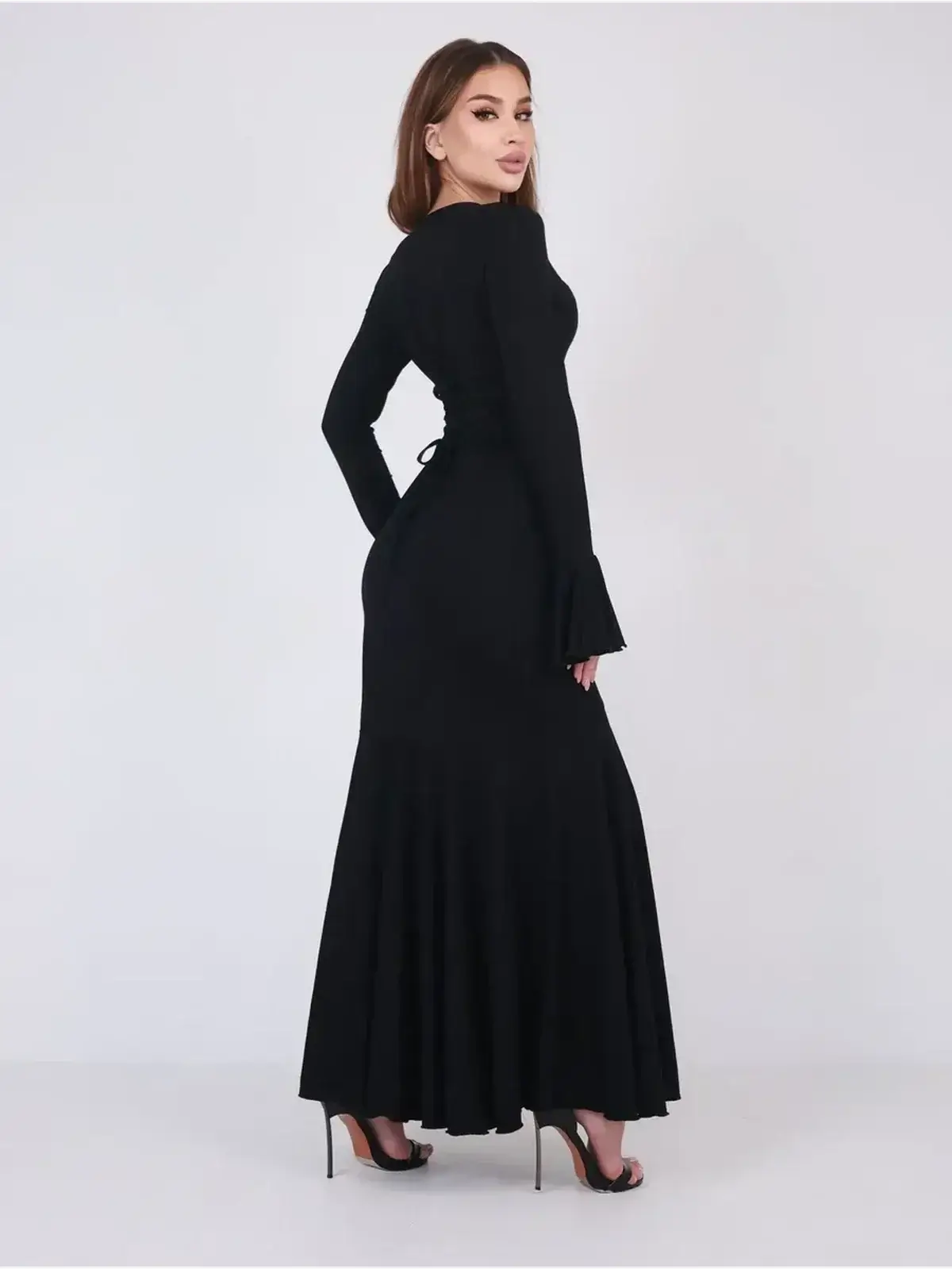 Back view of a model wearing the elegant Mirage Maxi Dress with flared cuffs and fishtail hem.