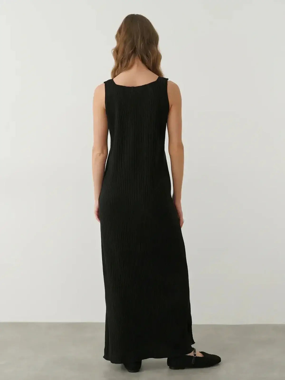 Back view of the Muse Knit Maxi Dress, showcasing a sleek black design with a ribbed texture and ankle-length silhouette.
