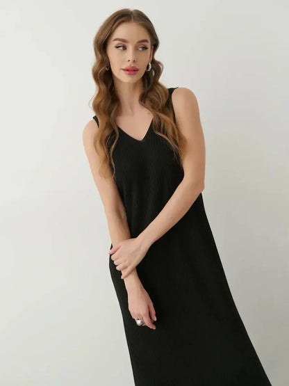 Model wearing the Muse Knit Maxi Dress, a sleek black sleeveless gown with a V-neckline and ribbed texture.