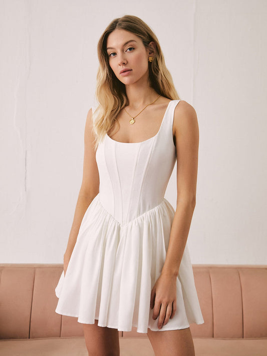 Model wearing the Nell Mini Dress, a white linen dress featuring a sculpted bodice and flared skirt, perfect for summer occasions.