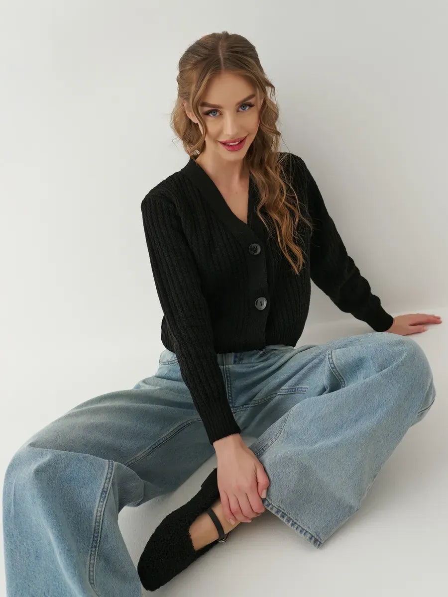 Stylish model wearing the Noir Cardigan by Lauven, an oversized cropped black knitwear, paired with wide-leg jeans.