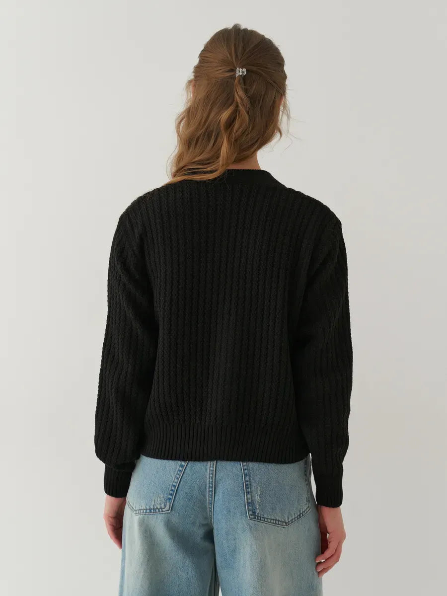 Back view of a woman wearing Noir Cardigan by Lauven, showcasing its oversized cropped design in black.