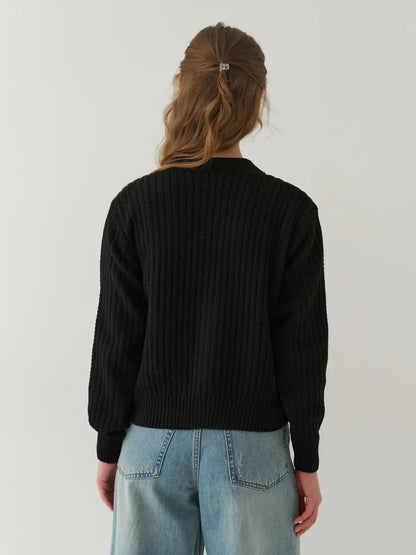 Back view of a woman wearing Noir Cardigan by Lauven, showcasing its oversized cropped design in black.