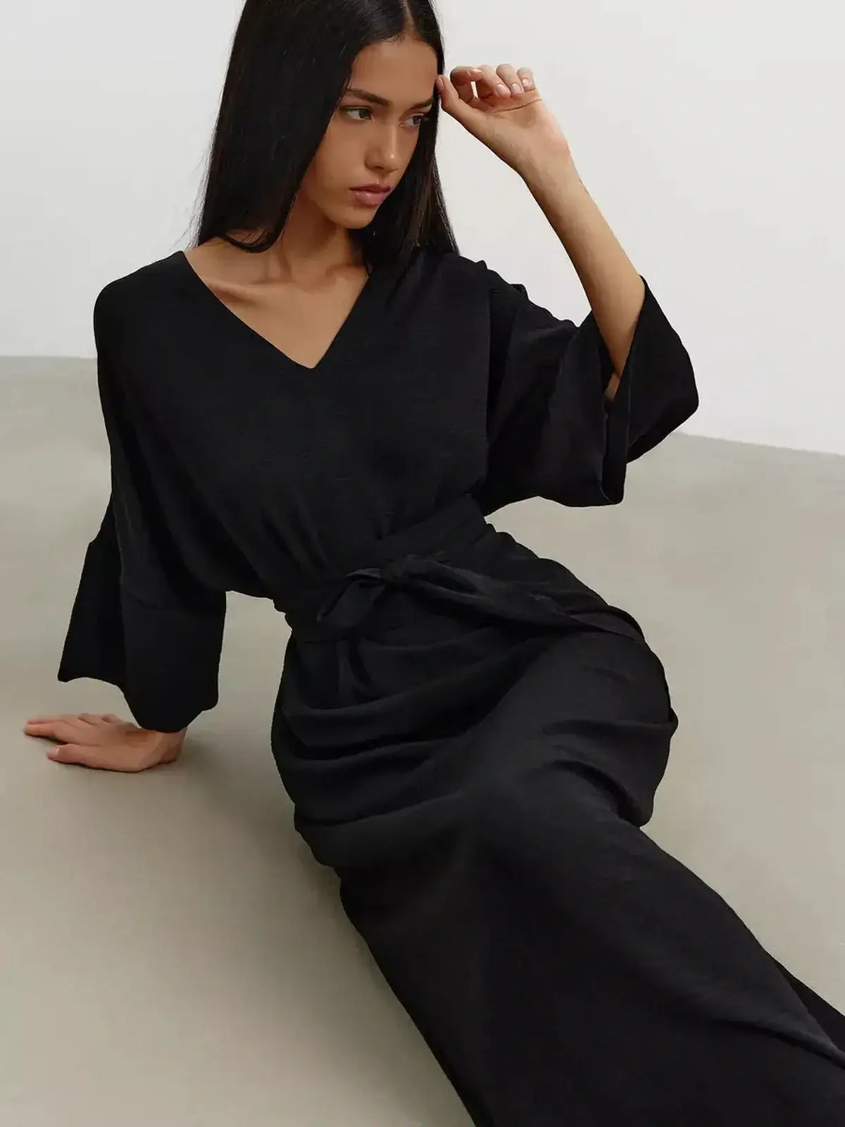 Model wearing the Noir Drift Maxi Dress, featuring kimono sleeves and a V-neckline, showcasing fluid elegance in black.