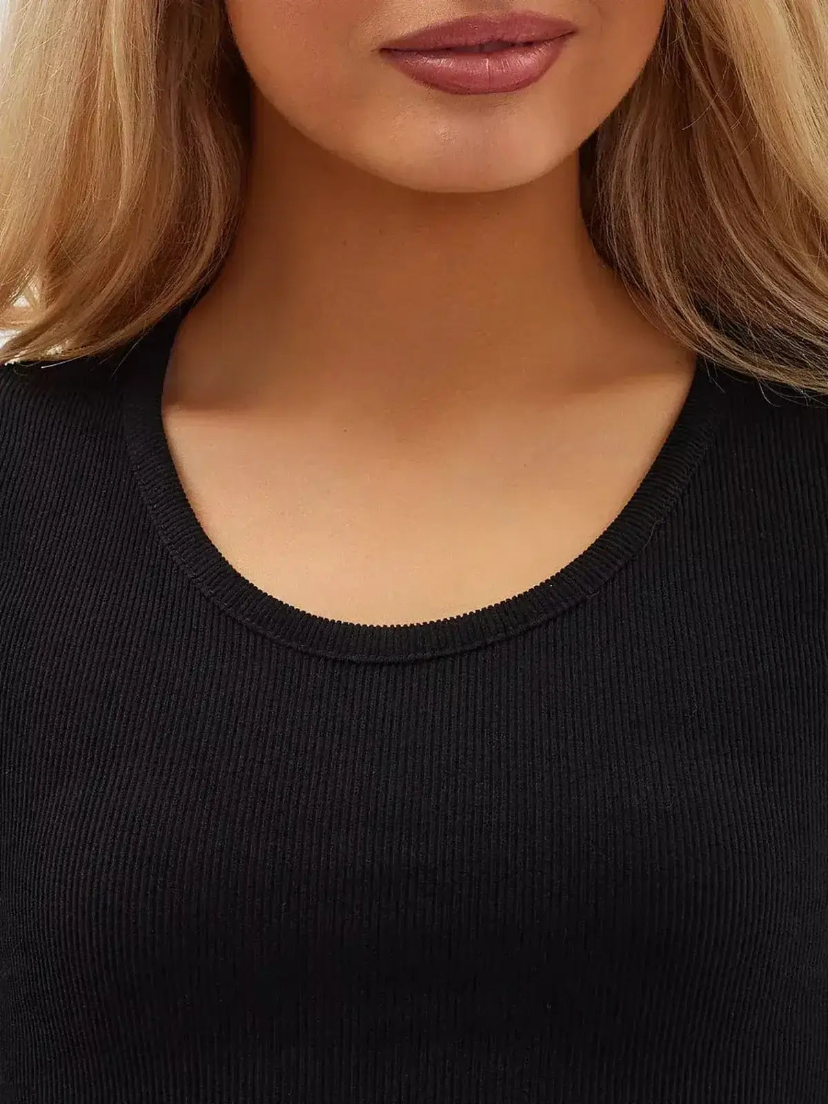 Close-up of a woman's neckline in a black ribbed fabric, showcasing elegance and style in women's clothing.