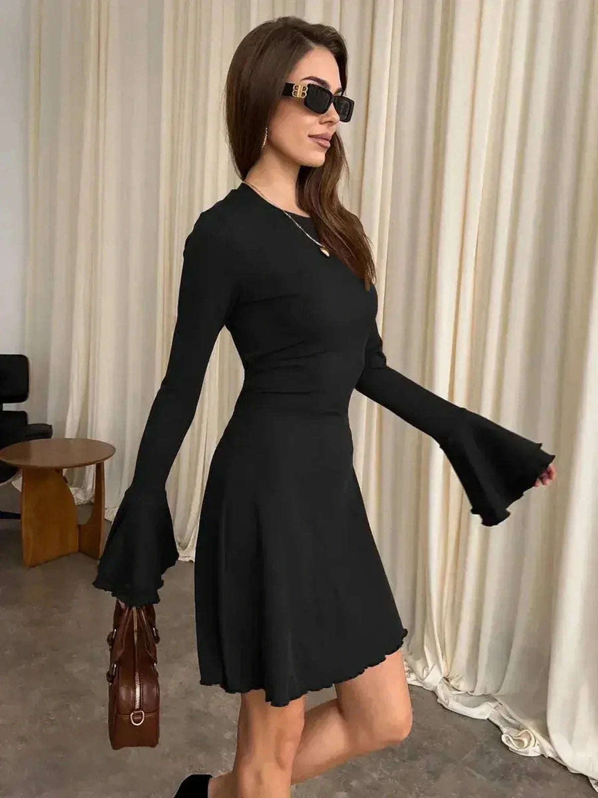 Model wearing the Noir Flare Mini black dress with flared cuffs, showcasing modern elegance and style.