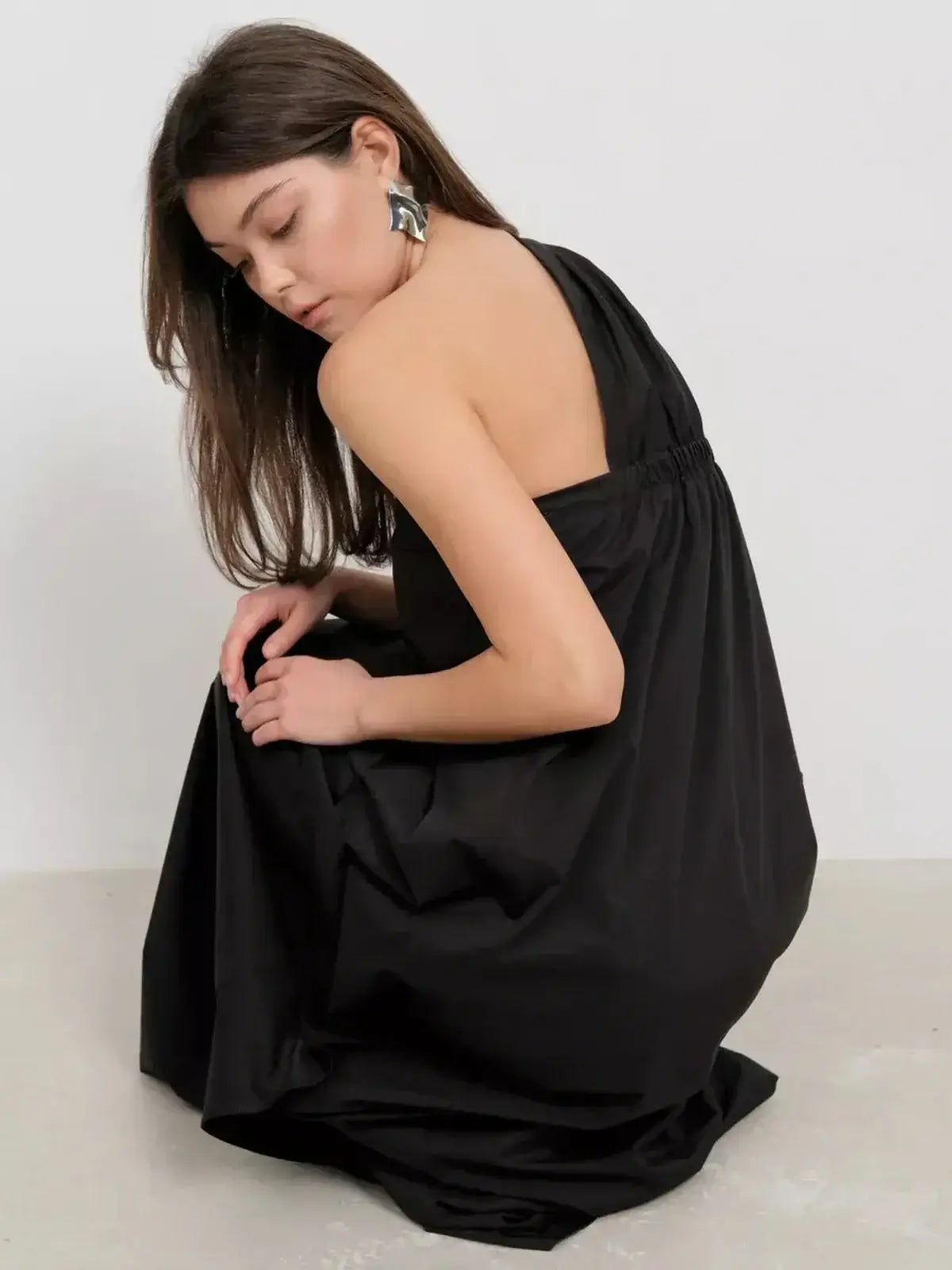 Model wearing a one-shoulder black maxi dress, showcasing the elegant drape and fluid design.