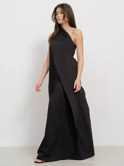 Black one-shoulder maxi dress showcasing draped elegance and a sculptural silhouette.