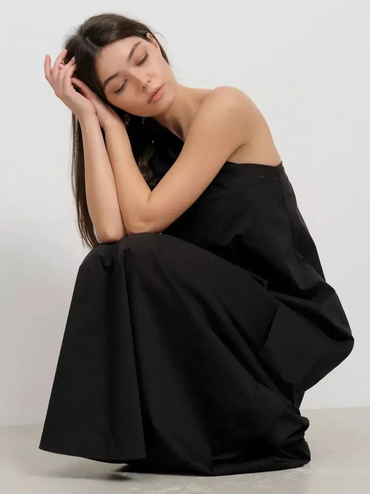 Model in a black one-shoulder maxi dress, showcasing draped elegance and modern sophistication.